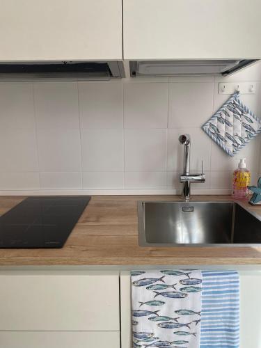 a kitchen with a stainless steel sink and white cabinets at Ostuni Ayla Apartments in Villanova di Ostuni