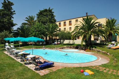 ein Pool mit Stühlen und Menschen schwimmen darin in der Unterkunft Alghero Resort Country Hotel & Spa in Alghero