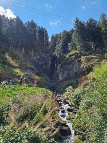 a group of people sitting on a hill next to a river at Tonale Ski-in AlpView Studio in Passo del Tonale
