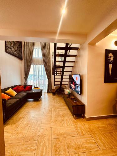 a living room with a black couch and a wooden floor at (A10) Hives Apartment in Lagos