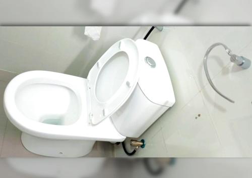 a white toilet in a bathroom with the lid up at Apartment 79 Hotel & Suite in Ikeja