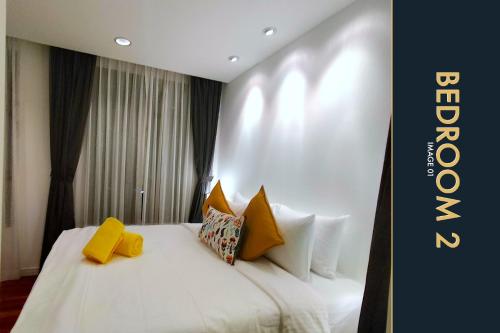 a hotel room with a white bed with yellow pillows at Luxury Apartment at a Bargain in Kamala Beach