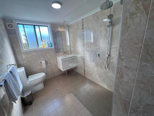 a bathroom with a shower and a toilet and a sink at Ocean Retreat in Nambucca Heads