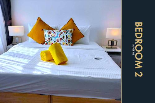 a white bed with two yellow pillows on it at Luxury Apartment at a Bargain in Kamala Beach