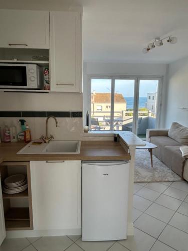 une cuisine avec un comptoir et un salon dans l'établissement Appartement traversant vue mer et étang, à Mauguio