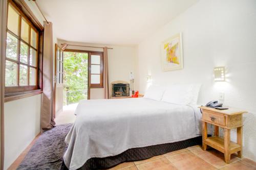 a bedroom with a white bed and a window at VELINN Hotel Ninho do Falcão in Monte Verde