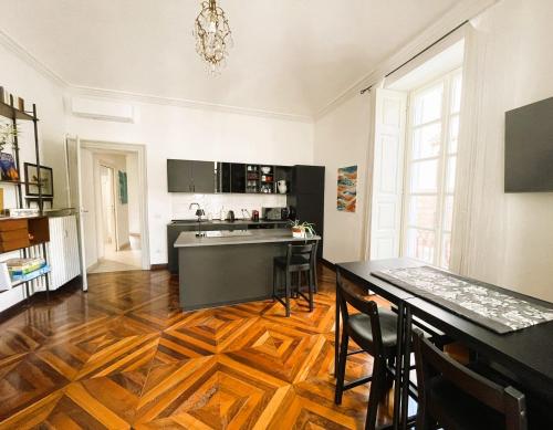 a kitchen with a wooden floor and a table with chairs at Emozione Torino - affascinante, silenzioso, in palazzo d'epoca pressi piazza Solferino in Turin