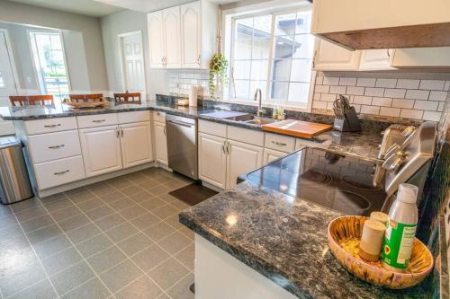 a kitchen with white cabinets and granite counter tops at Spacious Family Home with Hot Tub in Ellensburg