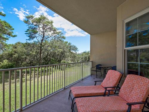 porche con sillas y balcón con vistas. en Sanctuary at Redfish 1119 by Newman-Dailey, en Santa Rosa Beach