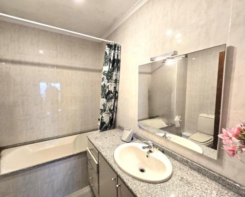 Un baño con lavabo, inodoro y espejo. en Holidays appartment, en Furadouro