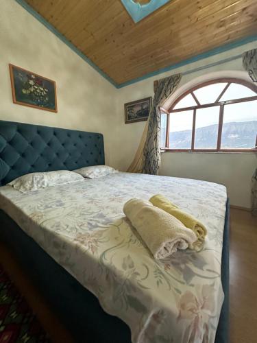 a bedroom with a bed with a blue headboard and a window at Villa Zeko in Gjirokastër