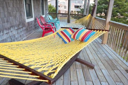 a hammock on a porch with chairs and a table at Dancing Dolphin 106 in Avon