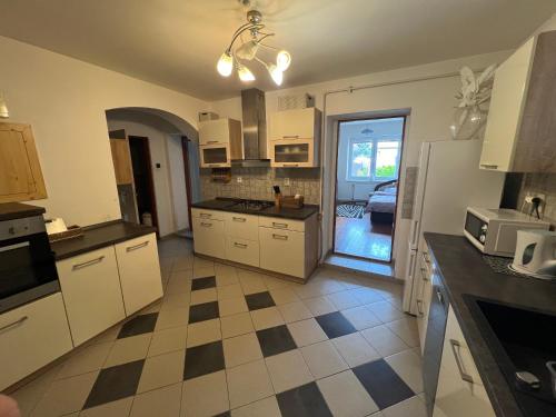 a kitchen with white cabinets and a checkered floor at -Self-Check- 4-bedroom family house with heated tub in Levice
