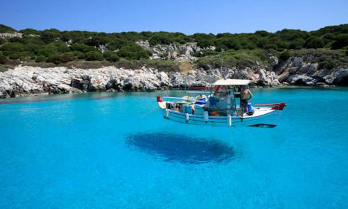 a boat in a body of blue water at Mary's House 1 in Skiros