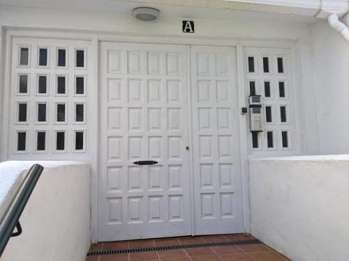 a white garage door with the letter a on it at Tranquil Oceanfront Escape, One-Bedroom Haven in Mijas