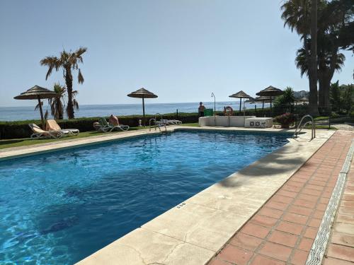 a swimming pool with the ocean in the background at Tranquil Oceanfront Escape, One-Bedroom Haven in Mijas