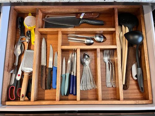 a wooden drawer filled with utensils at Ebony Apartment & Studio in La Gaulette