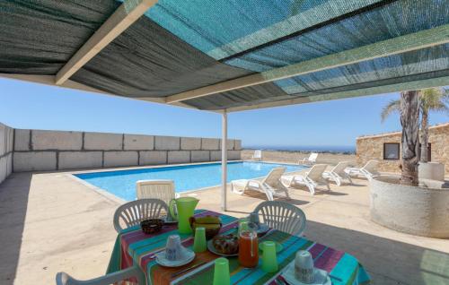eine Terrasse mit Tisch und Stühlen und ein Swimmingpool in der Unterkunft Cozy Home In Santa Croce Camerina in Santa Croce Camerina
