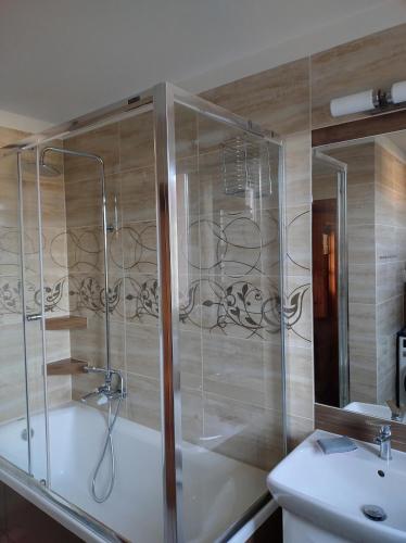 a bathroom with a shower and a tub and a sink at Pokoje Szczecińska in Szczecin