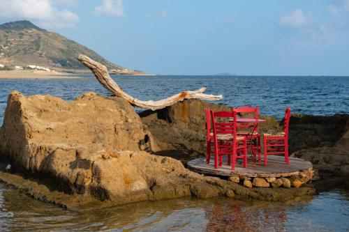 two red chairs sitting on a platform in the water at Mary's House 1 in Skiros