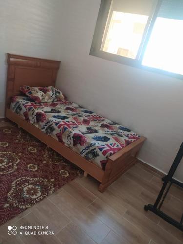 a bedroom with a bed and a window and a rug at Bouznika Dahoumi Mandarona in Bouznika