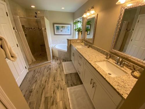 bagno con 2 lavandini, vasca e specchio di 8th Fairway Holiday Home Updated Southern Dunes a Haines City