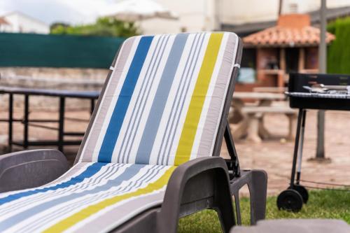 a striped lawn chair sitting in the grass at Casa de vacances Mary in Santa Eulalia de Ronsaná