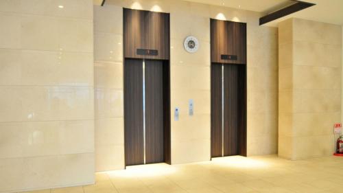 a hallway with three doors with a clock on the wall at Rikuchu Kaigan Grand Hotel - Vacation STAY 88515v in Kamaishi