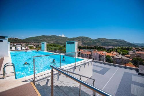 une grande piscine avec des gens dans l'eau dans l'établissement Pine 2 apartment in the center, à Trebinje