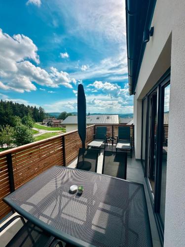 a balcony with a glass table and chairs on it at Apartmán Bezinka in Lipno nad Vltavou