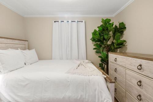 a bedroom with a white bed and a plant at Beachside Retreat! Cozy 1-bedroom W Private Yard in Dennis