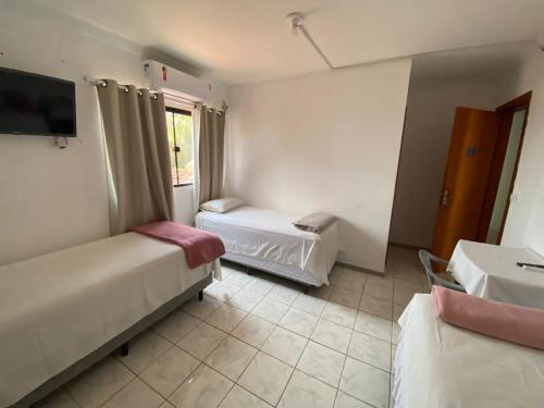 a hotel room with two beds and a tv at Hotel Califórnia in Tangara da Serra