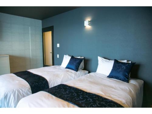 Dos camas con almohadas azules en una habitación. en Setouchi Resort Hotel - Vacation STAY 95864v, en Matsuyama