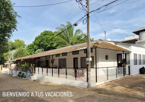 a white building with a fence in front of it at Casa villa con Jacuzzi, tobogán y BBQ in Carmen de Apicalá