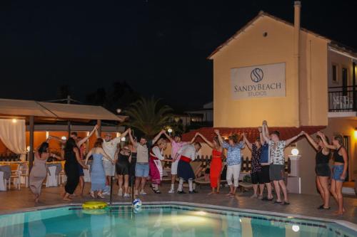 a group of people dancing by a pool at night at Sandy Beach Complex - Annexe Building in Kavos