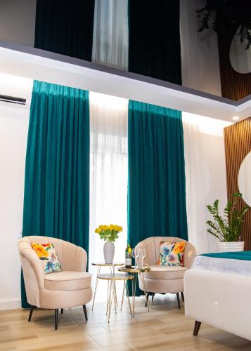 two chairs and a table in a room with green curtains at Josephine Apartment in Subotica