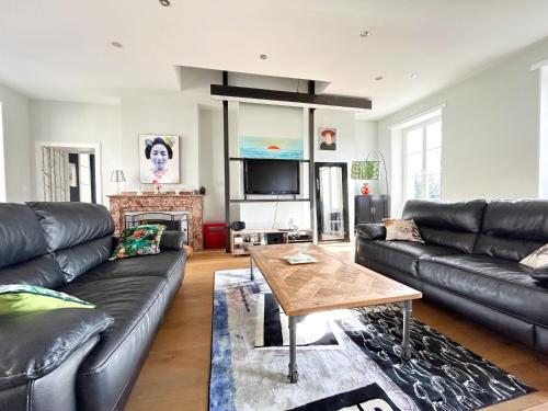 a living room with a black leather couch and a table at Bureau51– Centre Historique AUCH in Auch