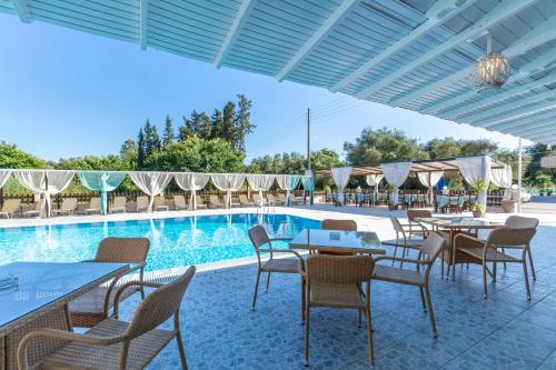 a patio with tables and chairs next to a pool at Sandy Beach Complex - Annexe Building in Kavos