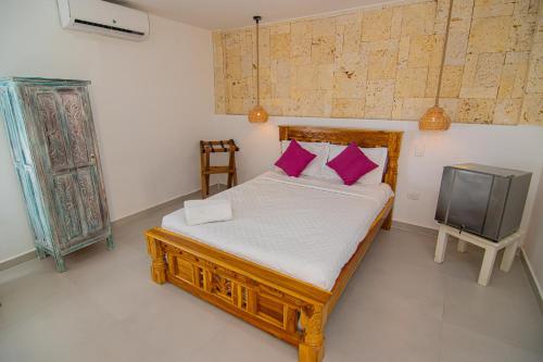 a bedroom with a bed with purple pillows and a tv at Casa Playa James in La Boquilla