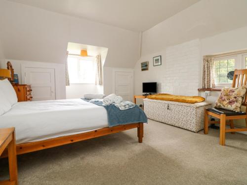 a bedroom with a large bed and a chair at Flushing Meadow in Helston