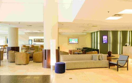 a lobby with a couch and tables and chairs at Hotel Luzeiros Fortaleza in Fortaleza