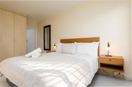a bedroom with a large white bed and a night stand at 31 Madison Palms East in Johannesburg