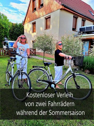 two women standing next to their bikes in a yard at Ferienwohnungen Haselhuhn in Hartau