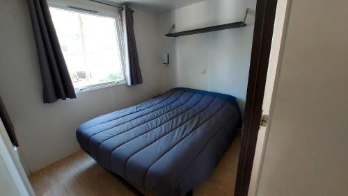 - un lit bleu dans une chambre avec fenêtre dans l'établissement camping marvilla les 7 fonds, à Agde