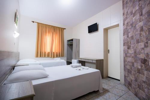 a bedroom with two white beds and a brick wall at Hotel Dan Inn Poços de Caldas - A melhor localização do Centro by Nacional Inn in Poços de Caldas
