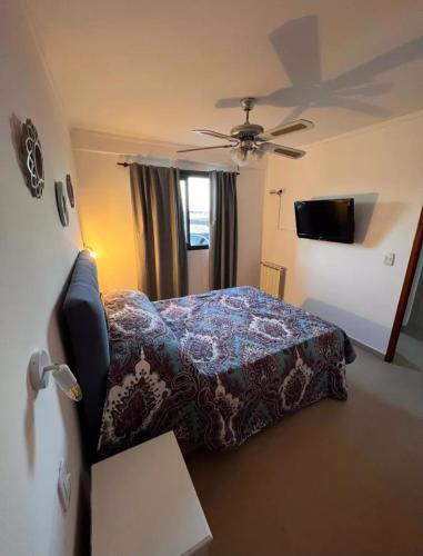 1 dormitorio con 1 cama y ventilador de techo en El Arenal Suite en Villa Gesell