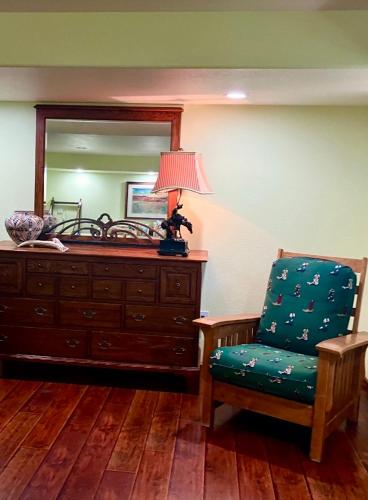 a chair and a dresser with a lamp and a mirror at Trail Boss King EnSuite-Prairie Rose B&B - 1200 sq ft Suite in Cheyenne