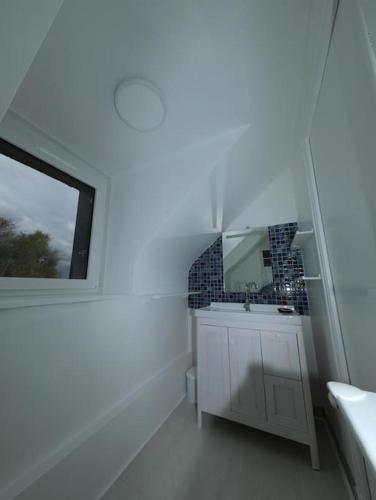 une salle de bain blanche avec un lavabo et un miroir dans l'établissement Ti Ar Familhou classée 3 étoiles, à Paimpol