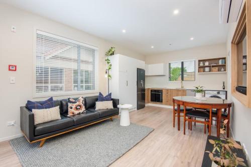 ein Wohnzimmer mit einer schwarzen Couch und einem Tisch in der Unterkunft George Little Stylish, Peaceful & Convenient in Dunedin