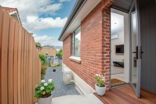 a brick house with a balcony with two potted plants at George Little Stylish, Peaceful & Convenient in Dunedin